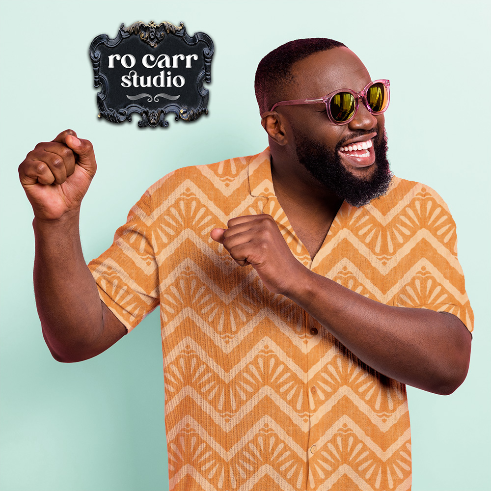 Bearded African American man in his 30s with big smile and arms raised in dance, wearing a short sleeve button down shirt featuring the "Moroccan Zig Zag" pattern