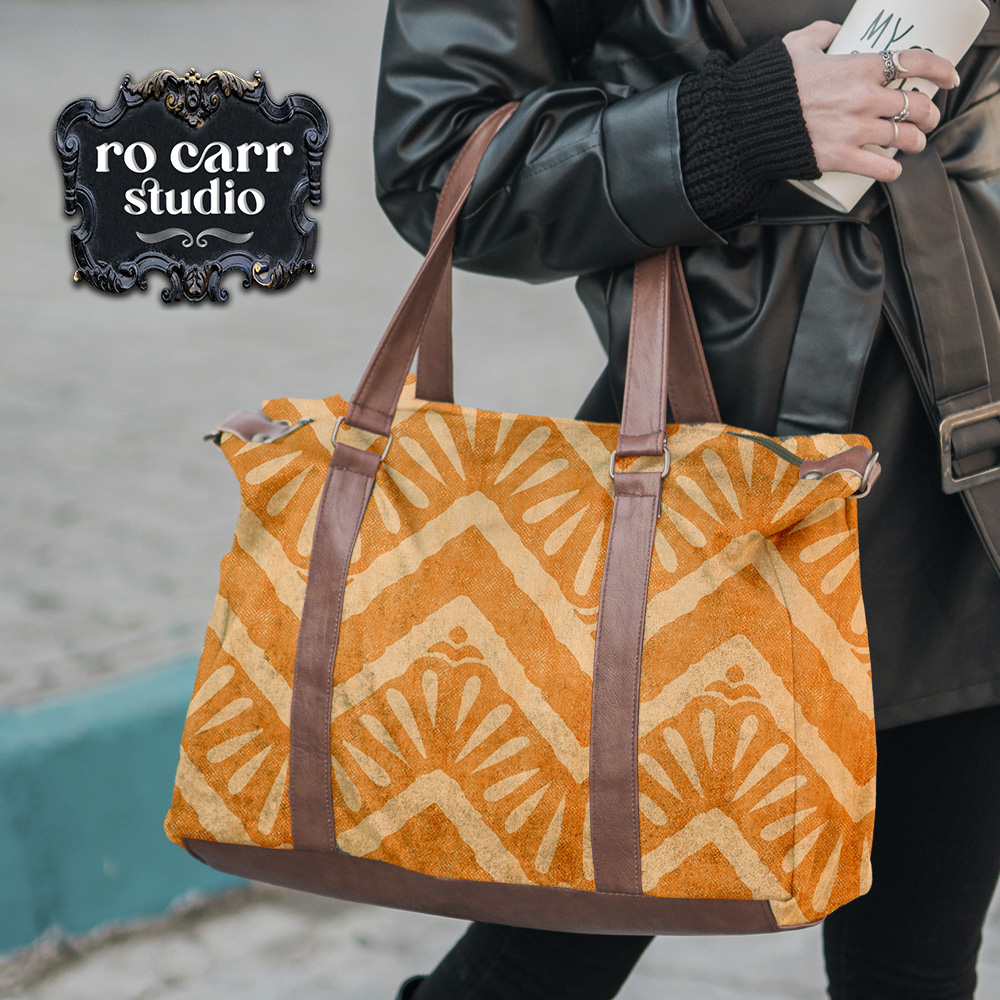 Close up photo of a large weekender tote bag with brown leather straps on the arm of a woman. The tote is printed with the "Moroccan Zig Zag" pattern.