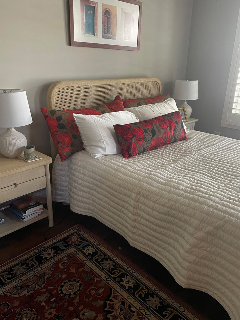 Queen bed with side tables, featuring three throw pillows made with Bees & Poppies in red fabric