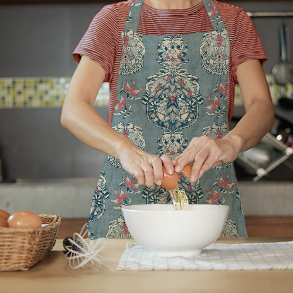 Christmas toile de jouy pattern shown in a mockup of an apron on a woman baking in the kitchen.