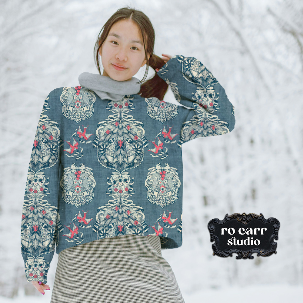 Young woman in a snowy scene, wearing a sweater printed with the toile pattern.
