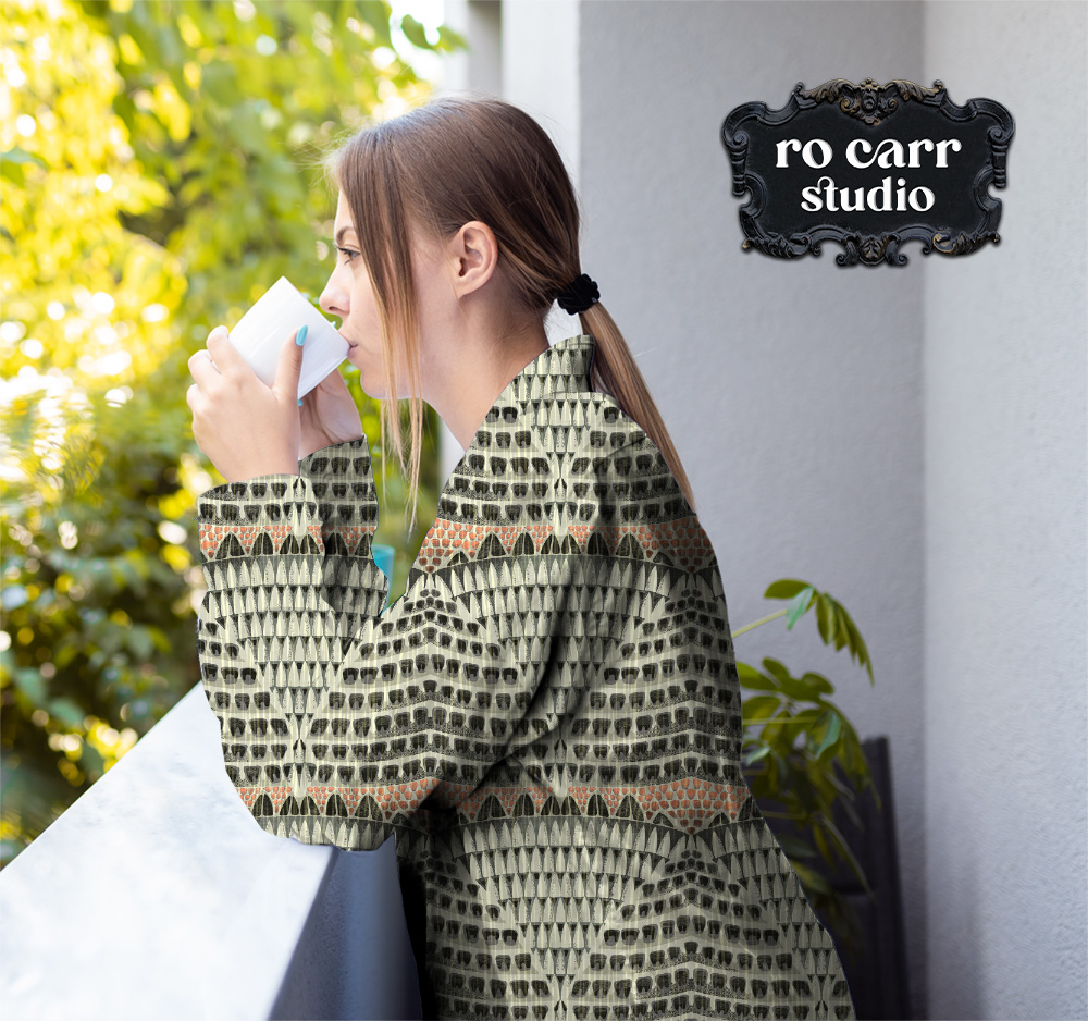 Woman drinking coffee, leaning against a patio wall, wearing a shirt made from fabric printed with the Armadillo pattern.