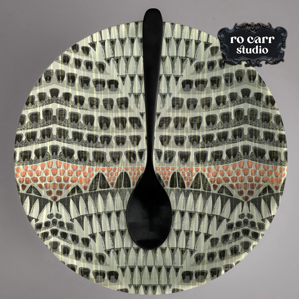 Dinner plate and black spoon, the plate is printed with the Armadillo pattern.