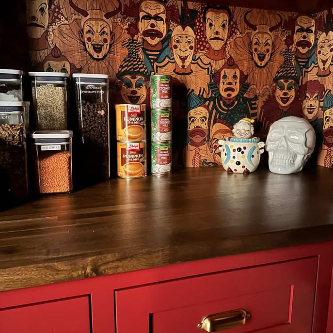 Dark red pantry shelves stocked with spices, with "Creepy Carnival Clowns" wallpaper peeking out between the jars and boxes.