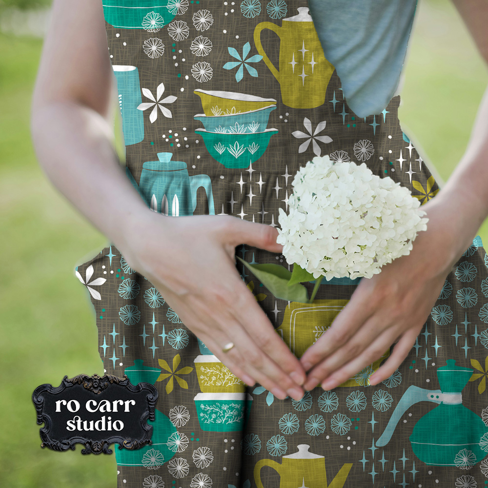Woman in a field with flower in her pocket, wearing an apron made with the pattern in teal.