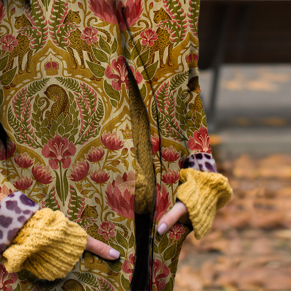 A close-up of a kimono-style garment printed with a damask leopard and tropical floral pattern in antique gold and rose red.