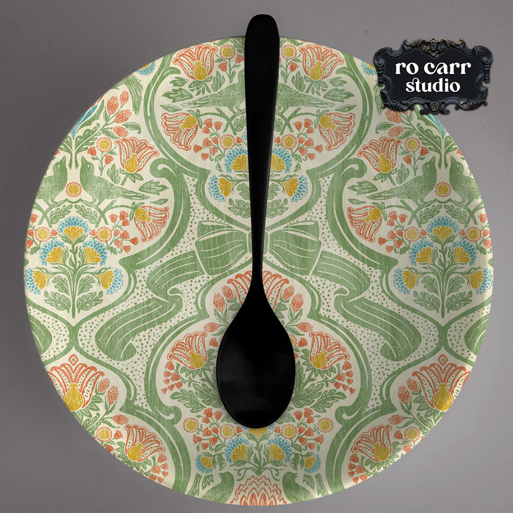 Round serving plate printed with a symmetrical botanical damask pattern centered on a large spoon motif.